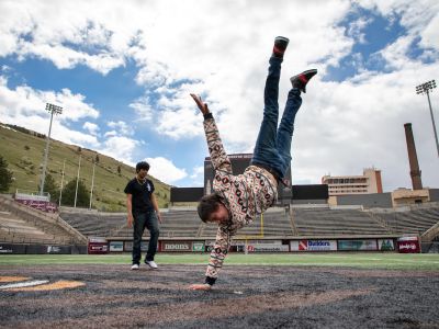 Student doing single handed hand-stand on the football field.