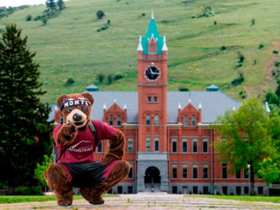 Monte crouching in front of main Hall pointing at you.