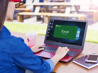 person sitting at a table with a laptop starting up the program excel