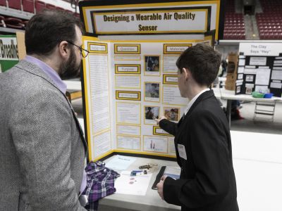 student pointing at their poster board