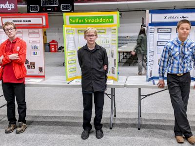 3 kids standing in front of boards