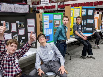 kids smiling at the science fair sitting down