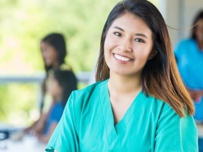 Photo of 30 year old female, smiling and wearing scrubs, links to "workforce"