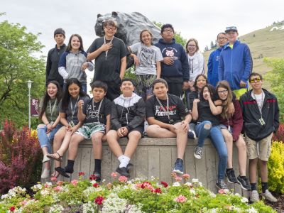 AIMS students pose in front of griz statue