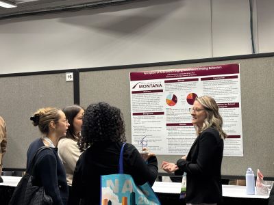 A graduate student pointing at her conference poster, explaining to three conference atendees