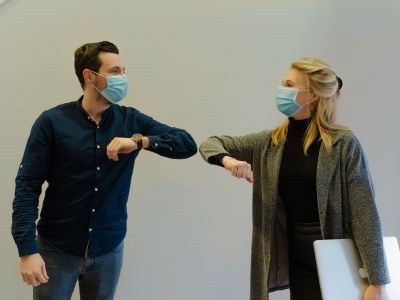 Photo of masked man and woman touching elbows in greeting
