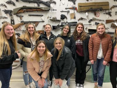 Crim Club students standing in front of a wall of firearms at the MT State Crime Lab