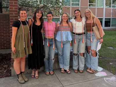 five students in front of Curry Health wearing graduation cords