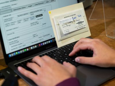 Someone using a laptop to fill out paperwork 
