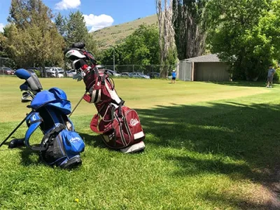 Two golf bags sit on the green at the UM Golf Course