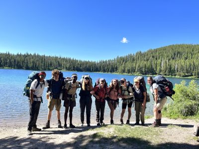 A group of students posing for a photo in nature with backpacks on 