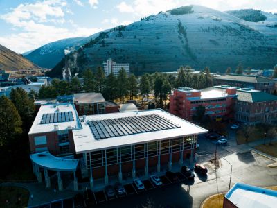 drone shot of the top of education building's solar panels with mount sentinel in the background