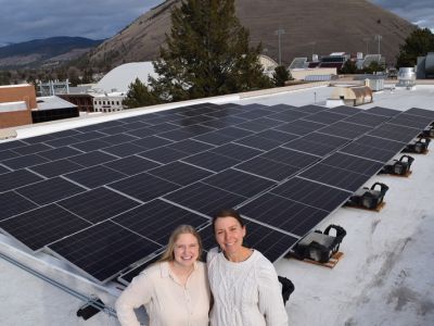 eva and tayli smile in front of the education building solar array