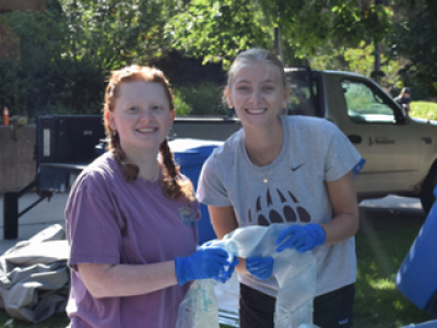 girls smiling while holding trash bags