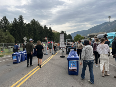 blue recycling bins lined up outside the gates as people enter the stadium.
