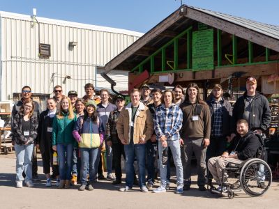 a large group of students poses outside a workshop as part of the ATG cognizant spring break