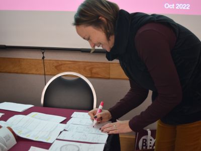 an employee is smiling as they write something down with a pink marker
