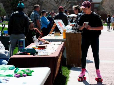 a student on roller skates pausing at tables at the sustainability fair