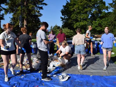 students help sort trash on the lawn of the UC