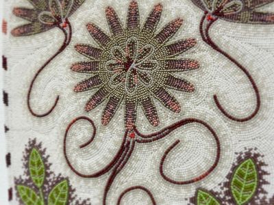 closeup of beadwork in purple, green, and ivory of a bitterroot flower