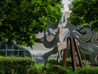 Statue on campus surrounded by green foliage