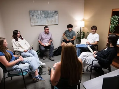 A group of students participate in a group discussion while sitting in a circle