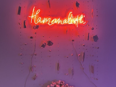 neon and ceramic installation artwork, neon says 'tlamanalistli' with ceramic masks and skulls
