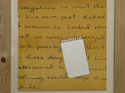 pine framed screenprint. yellow-orange background with handwritten text, image of a blank piece of torn out notepad paper in the center right