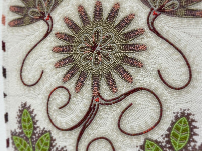closeup of beadwork in purple, green, and ivory of a bitterroot flower
