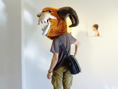 person wearing a mascot looking head piece inside an art gallery