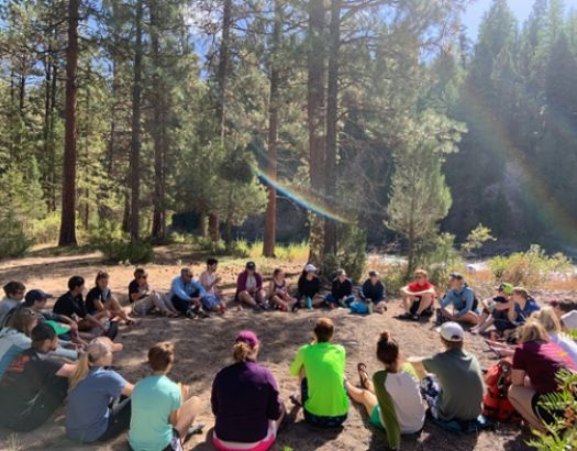 Photo of instructor and students sitting in circle outside.