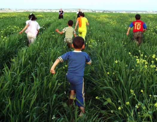 children run through a green field in Jordan