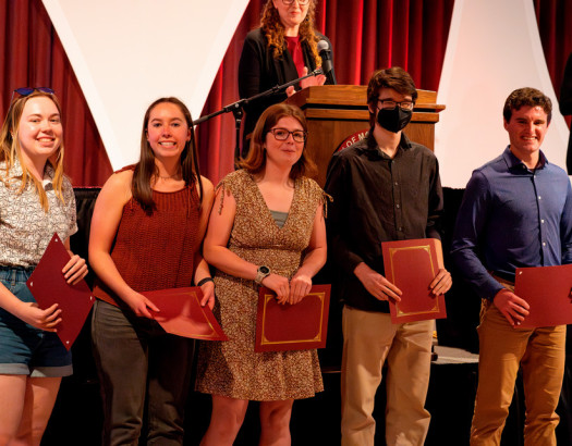 Group of students stand in front of a stage