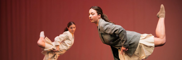 two students dancing standing on one foot with the other leg held high in the air