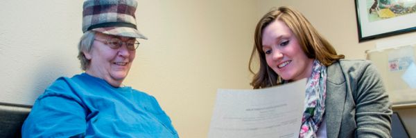 two people sitting together smiling and looking at a paper with text on it