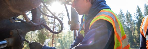 student working on the hydraulics of a construction vehicle