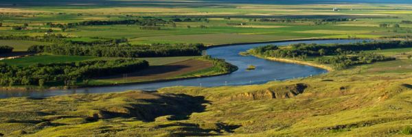 river winding through green farmland with some hills in the foreground