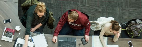 Overhead view of three students working on their laptops