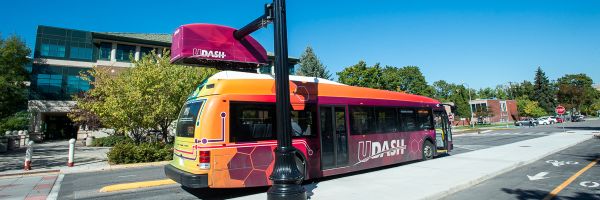 electric UM Dash bus sitting at a charging station on the UM campus