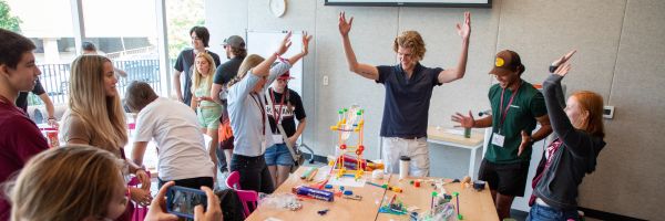group of students and staff celebrating around a table with a science experiment