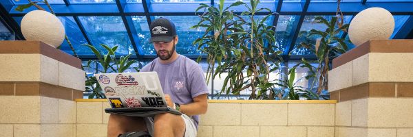 student working on a laptop in the gallagher business building
