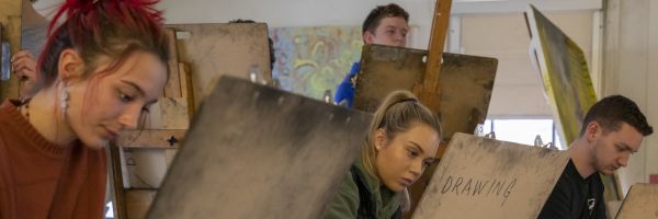 a group of students on multiple levels working on easels 
