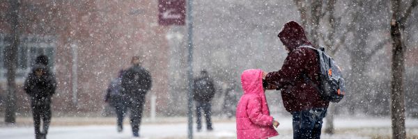 parent adjusting childs coat while they stand outside in the snow on the UM campus