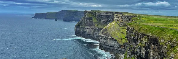 sharp rocky cliffs along a seashore with green plains 
