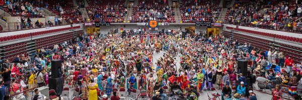 large group of people in traditional Native American clothing in the Adams Center