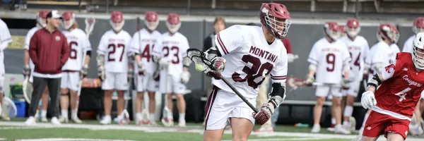 Griz lacrosse player cradles a ball in the stick as he looks downfield