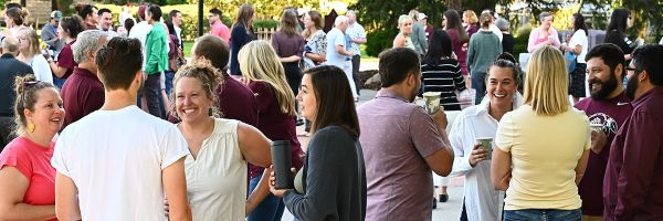 UM employees standing outside in various groups drinking coffee and chatting