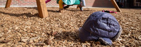 discarded kids winter cap on the wood chips of a playground