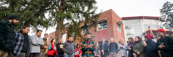 people standing a circle watching a presentation outside of the Payne Family Native American Center