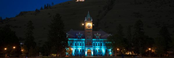 University Hall lit up at night with the M of the M trail behind covered in lights